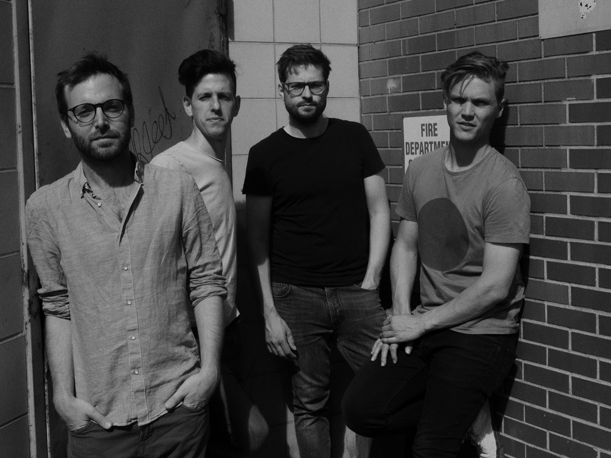The four band members of Ensemble Nikel standing in front of a brick wall.