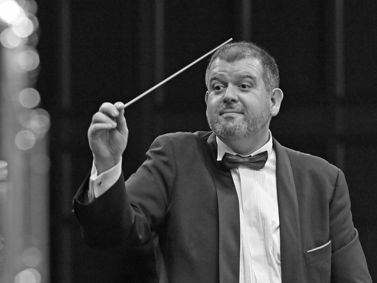 Carlo Balmelli dirige avec la baguette de chef d'orchestre levée.